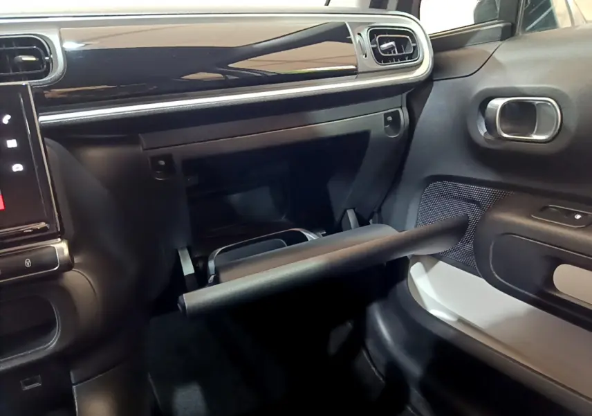 Intérieur côté passager de la Citroën C3 beige 2022 avec boîte à gants ouverte et tableau de bord noir brillant.
