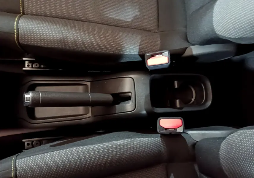 Vue plongeante sur la console centrale noire avec frein à main et ceintures rouges de la Citroën C3 beige 2022