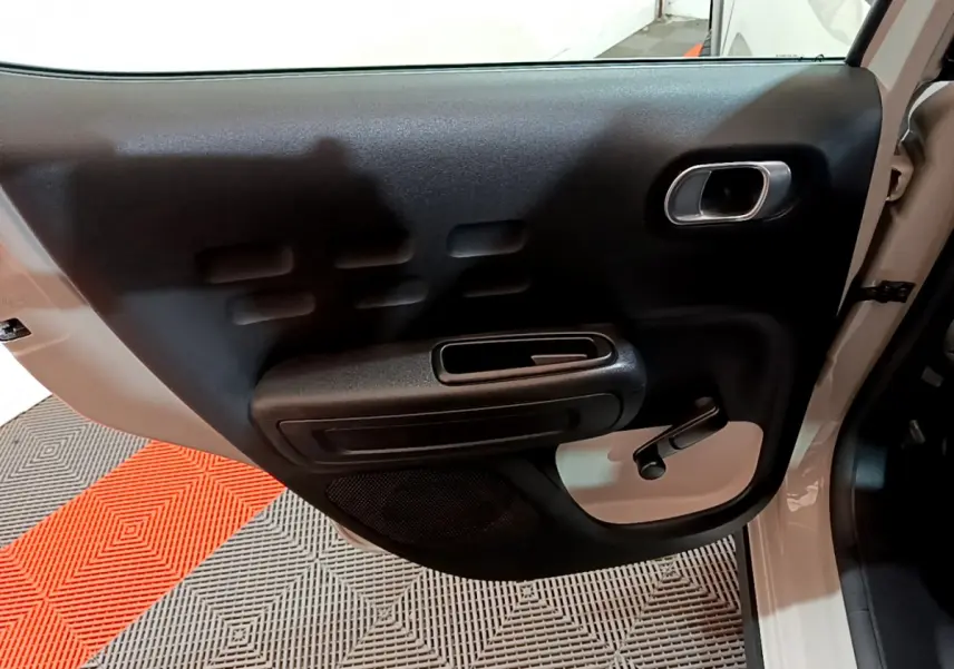 Vue rapprochée de la porte arrière gauche beige de la Citroën C3 2022 avec poignée manuelle et accoudoir noir.