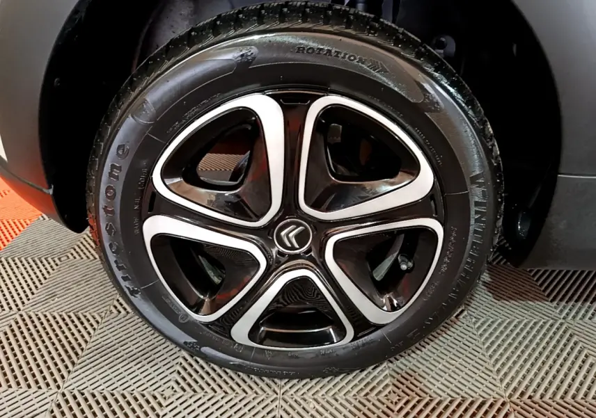 Gros plan sur la roue avant droite d'une Citroën C3 beige 2022 avec jante alliage noire et argentée distinctive.