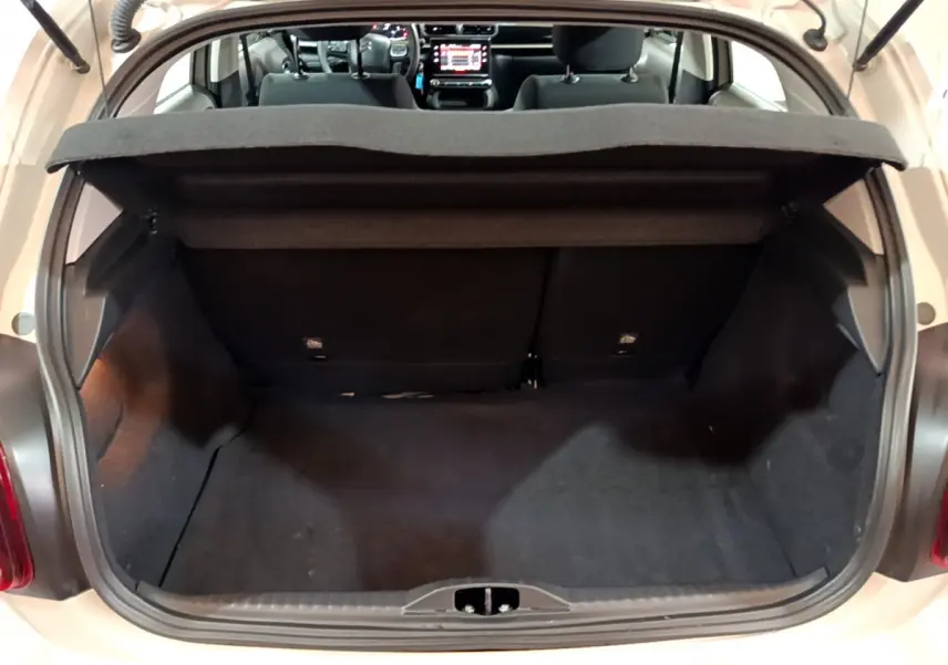Coffre ouvert d'une Citroën C3 beige 2022, vue arrière montrant l'habitacle et l'écran tactile du tableau de bord.