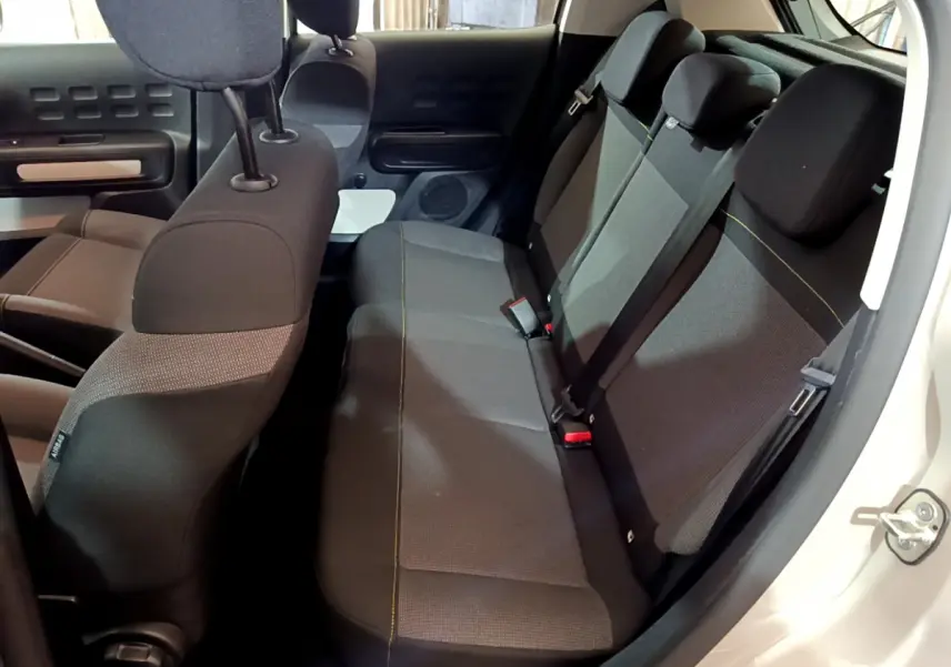 Vue intérieure côté droit sur la banquette arrière grise de la Citroën C3 beige, avec appuie-têtes et ceintures visibles.