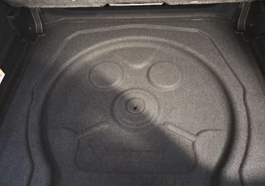 Coffre vide du Volkswagen Tiguan 2024, vue plongeante sur le compartiment de rangement gris foncé.