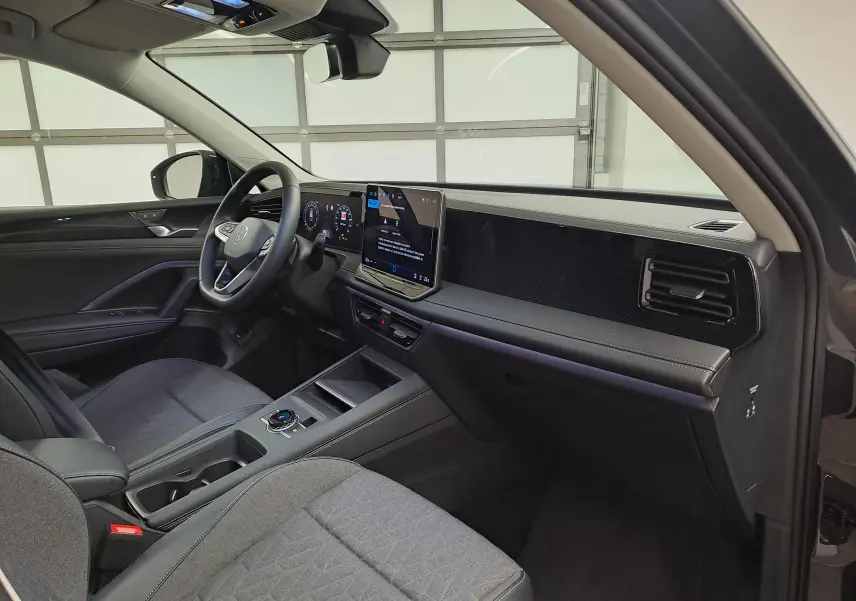 Intérieur avant droit du Volkswagen Tiguan 2024 gris Urano, tableau de bord moderne avec écran tactile central et volant multifonction.