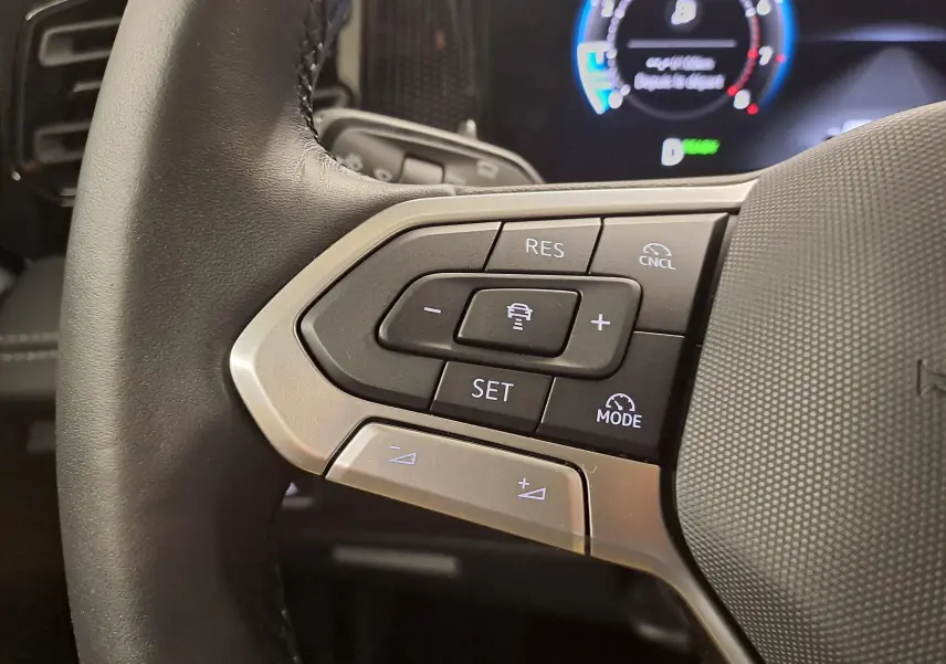 Gros plan sur les commandes à gauche du volant du Volkswagen Tiguan 2024, avec boutons de régulateur de vitesse et assistant de conduite.