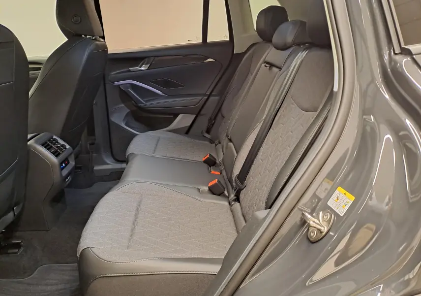 Vue intérieure côté droit des sièges arrière du Volkswagen Tiguan 2024 gris Urano avec sellerie tissu et cuir.