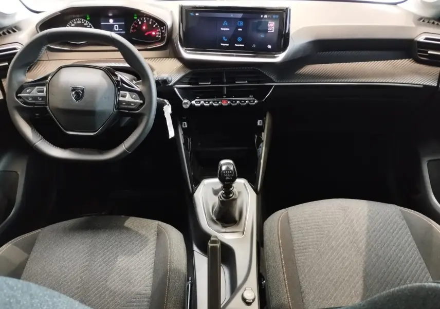 Vue intérieure avant de la Peugeot 208 2025 avec volant compact, écran tactile 10 pouces et levier de vitesse manuel.