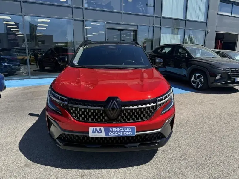 Vue avant d'un Renault Austral rouge flamme 2023 avec calandre noire à motif géométrique et logo central proéminent.