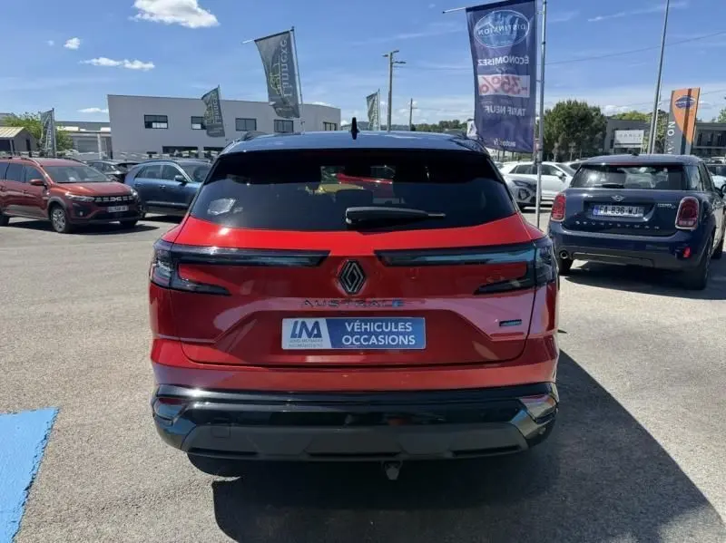 Vue arrière d'un Renault Austral rouge flamme 2023, version hybride, avec feux arrière fins et logo central distinctif.