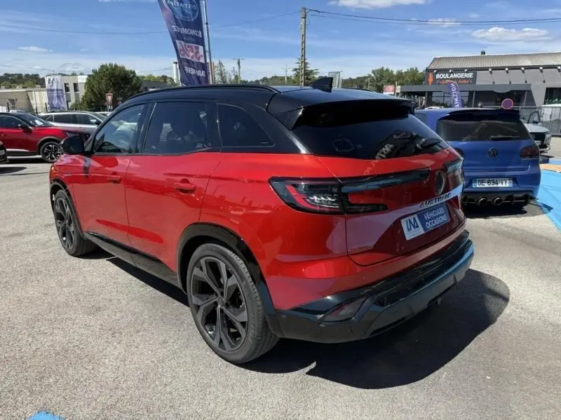 Vue 3/4 arrière droite du Renault Austral rouge flamme avec toit noir et jantes noires distinctives.