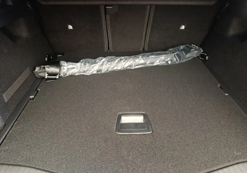 Vue intérieure du coffre gris foncé de la Citroën C5 Hybride 2025 avec un parapluie emballé posé à plat.