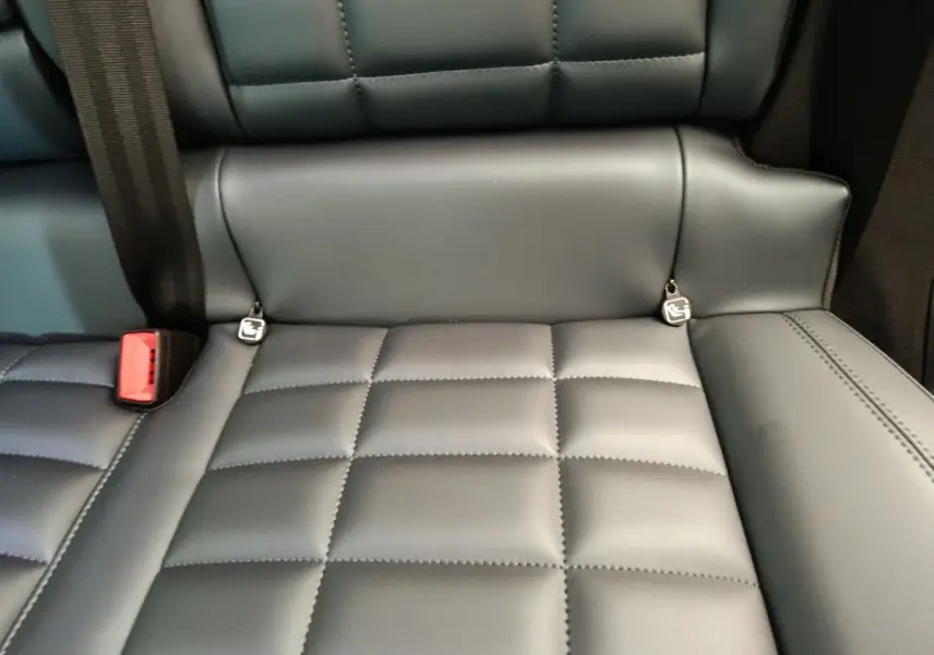 Gros plan sur la banquette arrière en cuir gris foncé de la Citroën C5 Hybride 2025 avec ceintures et ancrages Isofix visibles.