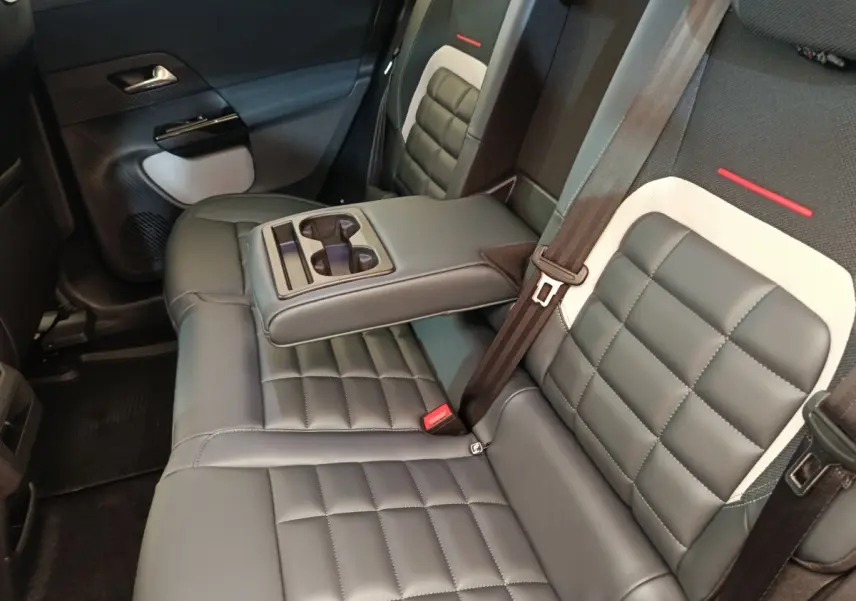 Vue intérieure sur la banquette arrière gris foncé de la Citroën C5 Hybride avec accoudoir central et porte-gobelets intégrés.
