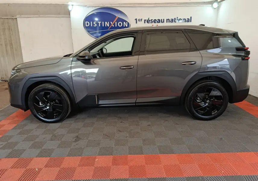 Vue de profil côté gauche d'une Citroën C5 hybride gris foncé avec jantes noires, stationnée en intérieur.