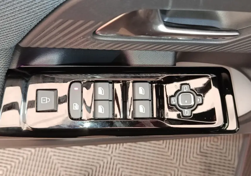 Gros plan sur les commandes de lève-vitres et rétroviseurs côté conducteur d'une Citroën C5 hybride gris foncé.