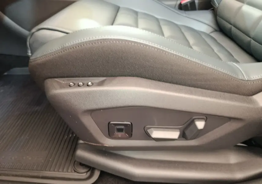 Gros plan sur les commandes de réglage électrique du siège avant droit en cuir gris foncé de la Citroën C5 hybride 2025.