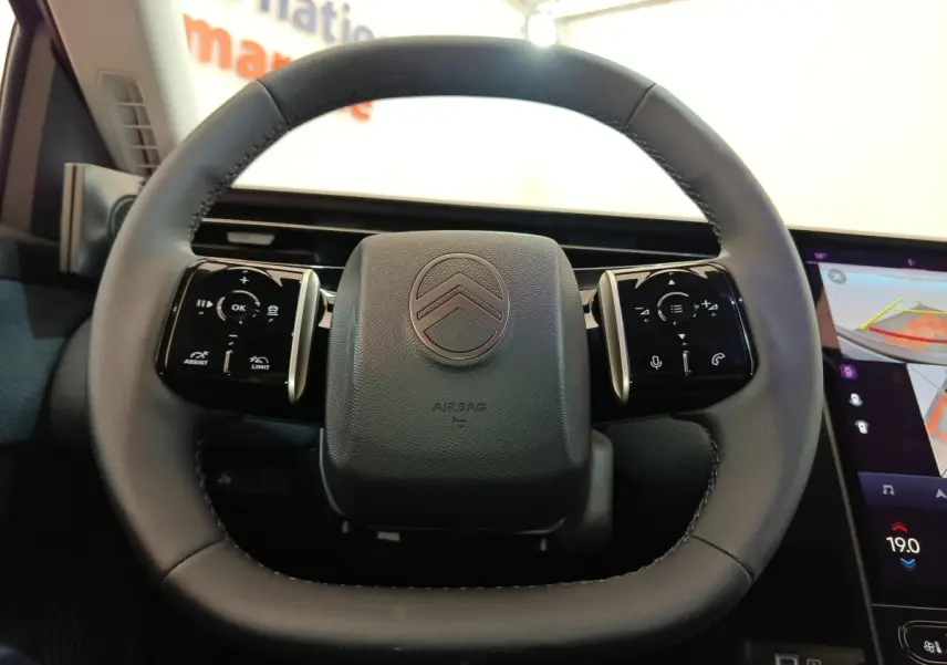 Volant cuir noir de Citroën C5 Hybride 2025 vu de face avec commandes tactiles et écran tactile latéral visible.