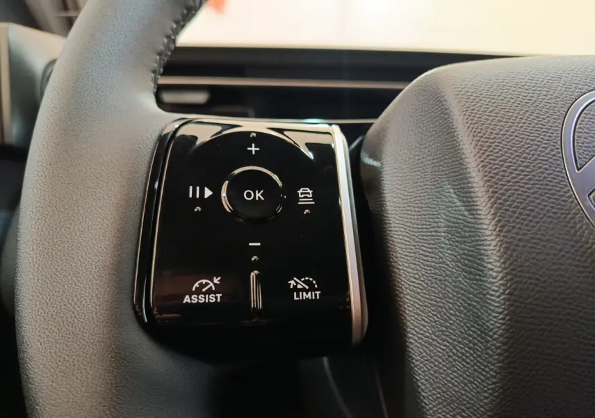 Gros plan sur les commandes multifonctions du volant cuir gris foncé de la Citroën C5 hybride 2025.