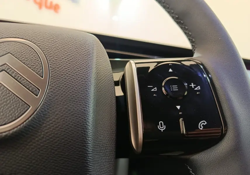 Gros plan sur les commandes multifonctions noires à droite du volant cuir de la Citroën C5 hybride 2025.