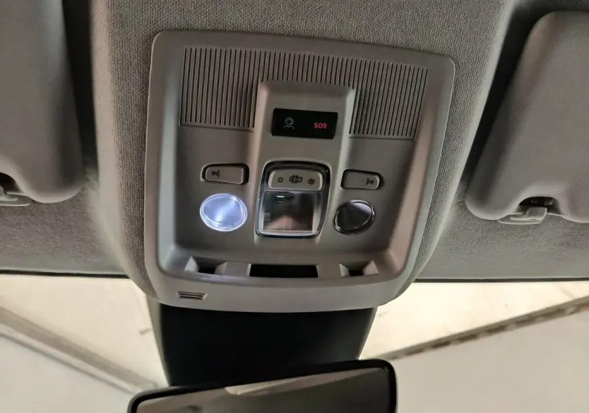 Vue intérieure en plongée sur la console de toit gris clair avec boutons d’éclairage et alerte SOS de la Citroën C5 hybride.