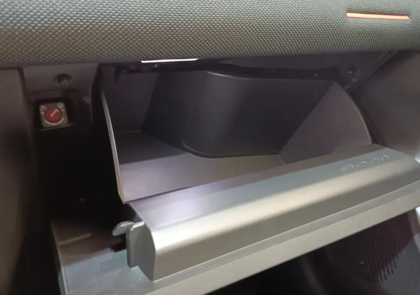 Vue rapprochée de la boîte à gants ouverte côté passager dans l’habitacle sombre d’une Citroën C5 Hybride gris foncé.