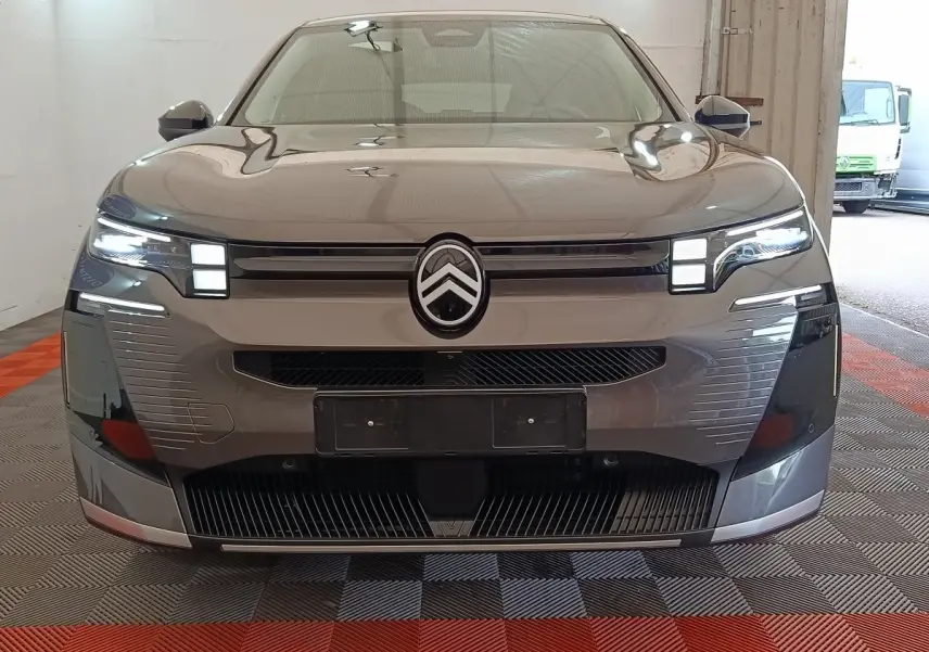 Vue frontale d'une Citroën C5 hybride gris foncé avec phares LED allumés et calandre distinctive.