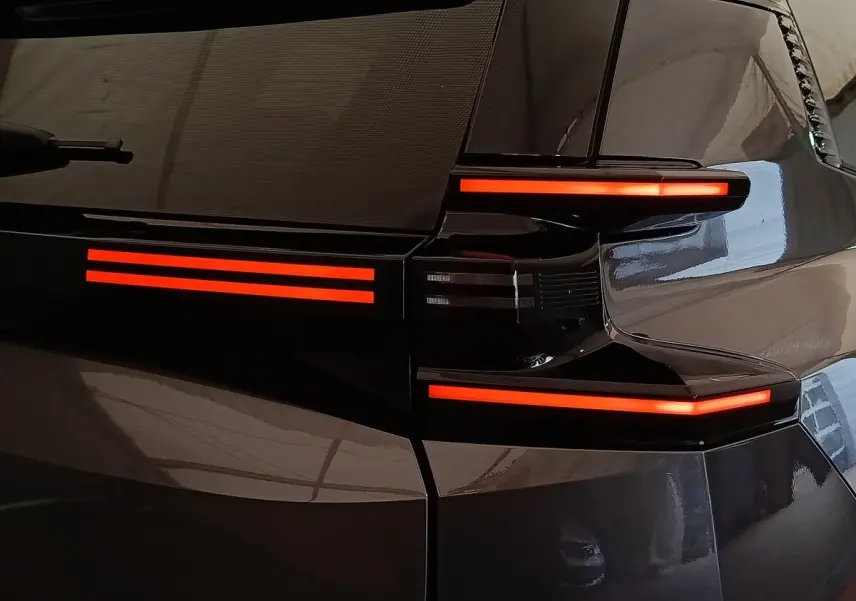 Feux arrière allumés en rouge sur la partie gauche d'une Citroën C5 hybride gris foncé, vue en gros plan.
