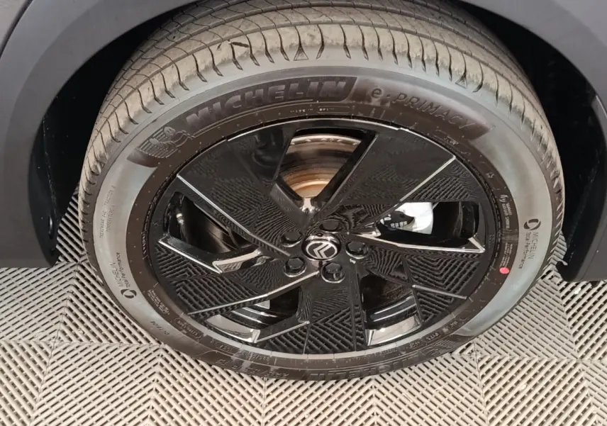 Gros plan sur la roue avant droite noire brillante avec logo Citroën et pneu Michelin e.Primacy.