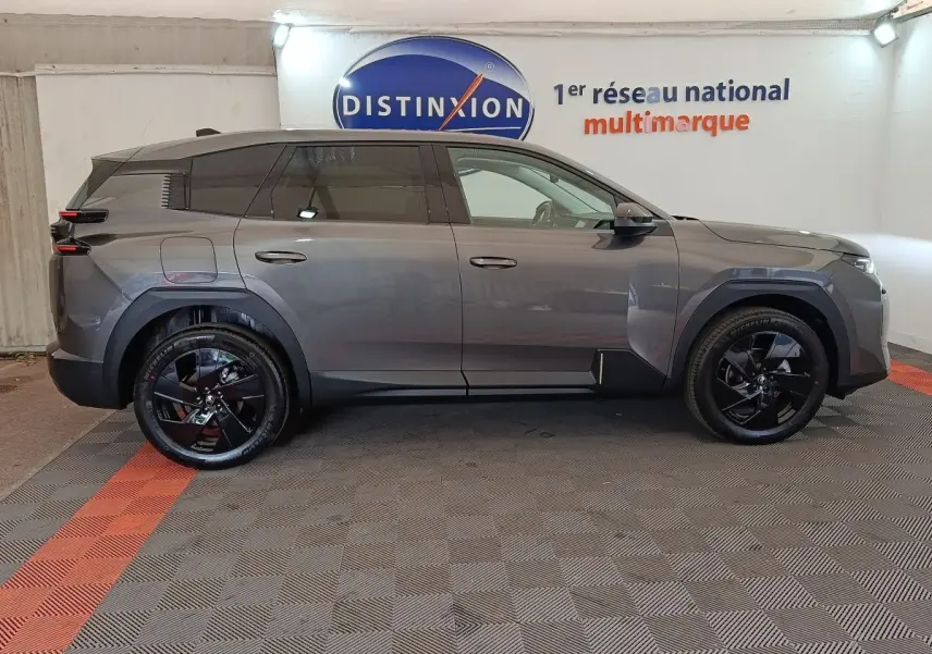 Vue de profil côté gauche d'une Citroën C5 hybride gris foncé avec jantes noires brillantes dans un showroom.