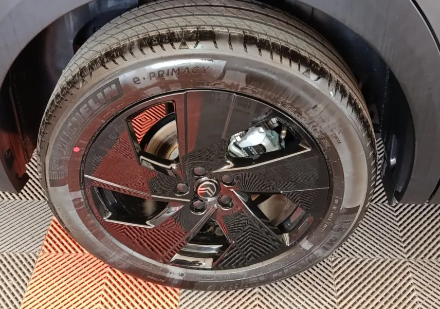 Gros plan sur la roue avant droite d'une Citroën C5 hybride gris foncé avec jante noire au design moderne.