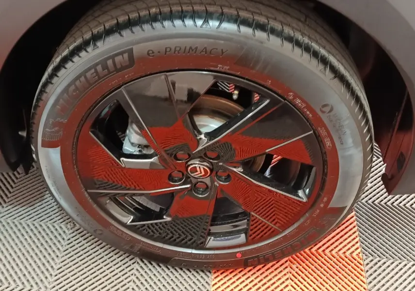 Gros plan sur la roue avant droite de la Citroën C5 hybride gris foncé avec jante noire brillante et logo Citroën central.