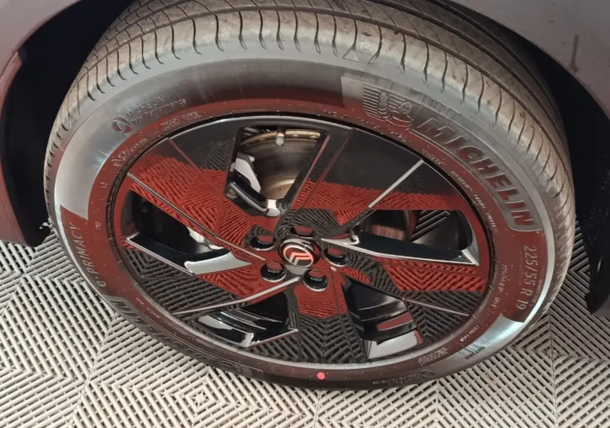 Gros plan sur la roue avant droite avec jante noire brillante et pneu Michelin du Citroën C5 hybride gris foncé.
