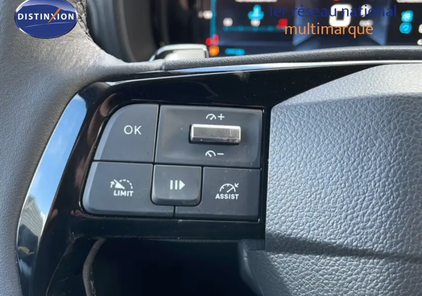 Gros plan sur les commandes au volant noir du Citroën Berlingo blanc glacier, mettant en valeur les boutons d'assistance et de limitation.