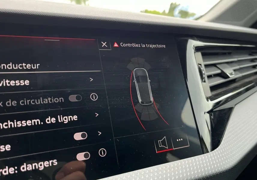 Vue rapprochée de l'écran central de l'Audi A1 Allstreet jaune Python affichant l'aide au stationnement avec trajectoire.