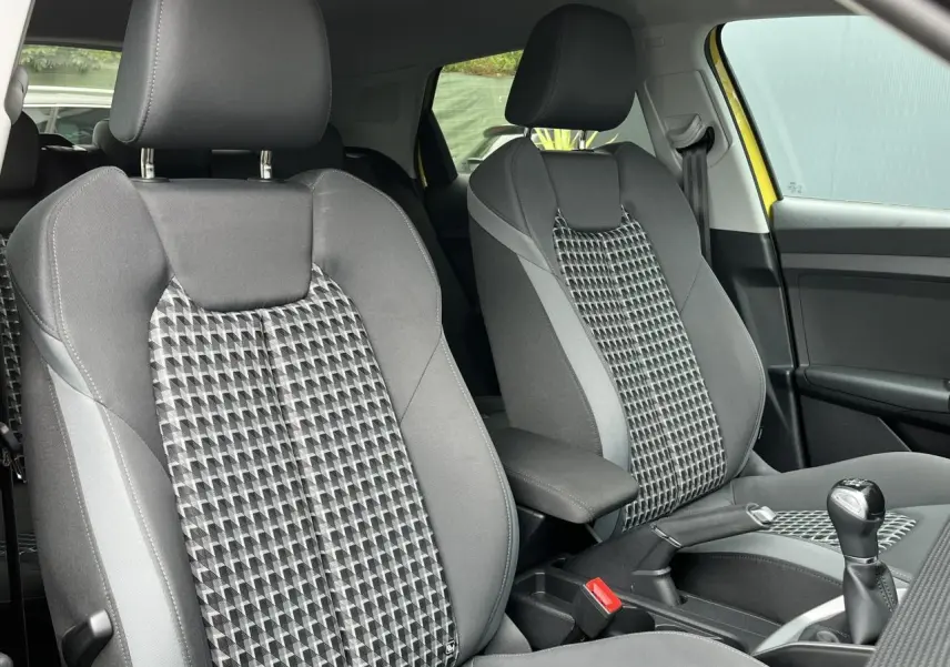 Gros plan sur les sièges sport gris à motifs géométriques de l'Audi A1 Allstreet jaune Python, avec accoudoir central visible.