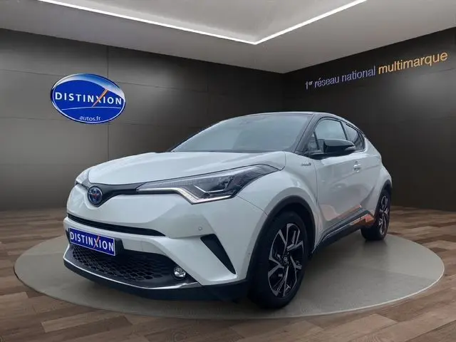 Toyota C-HR Hybride blanc toit noir en 3/4 avant droit, avec jantes noires et détails modernes visibles
