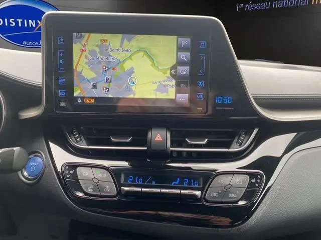 Tableau de bord du Toyota C-HR Hybride 2018 avec écran tactile GPS et commandes climatisation en vue frontale.