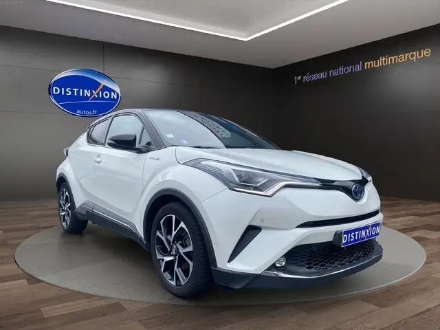 Toyota C-HR Hybride blanc toit noir en 3/4 avant droit, avec jantes alliage et calandre distinctive showroom