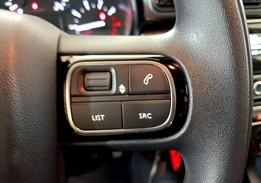 Gros plan sur les commandes multifonctions du volant noir de la Citroën C3 PureTech 68 BVM Feel 2018.