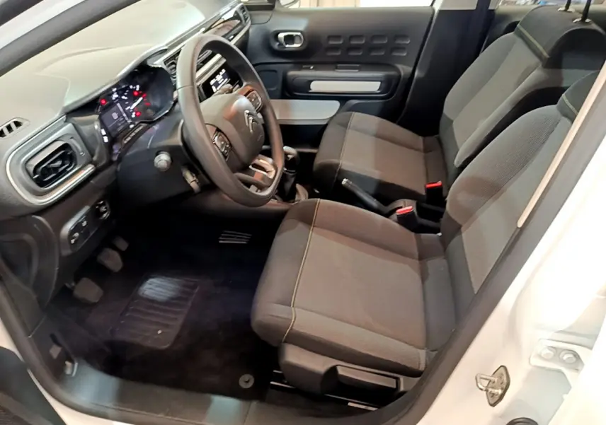 Intérieur avant droit d'une Citroën C3 blanche 2018, sièges tissu gris et tableau de bord avec volant multifonctions.
