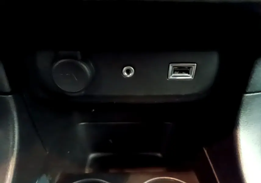 Prise USB, prise jack et allume-cigare dans la console centrale d'une Citroën C3 blanche PureTech 68 BVM Feel 2018.