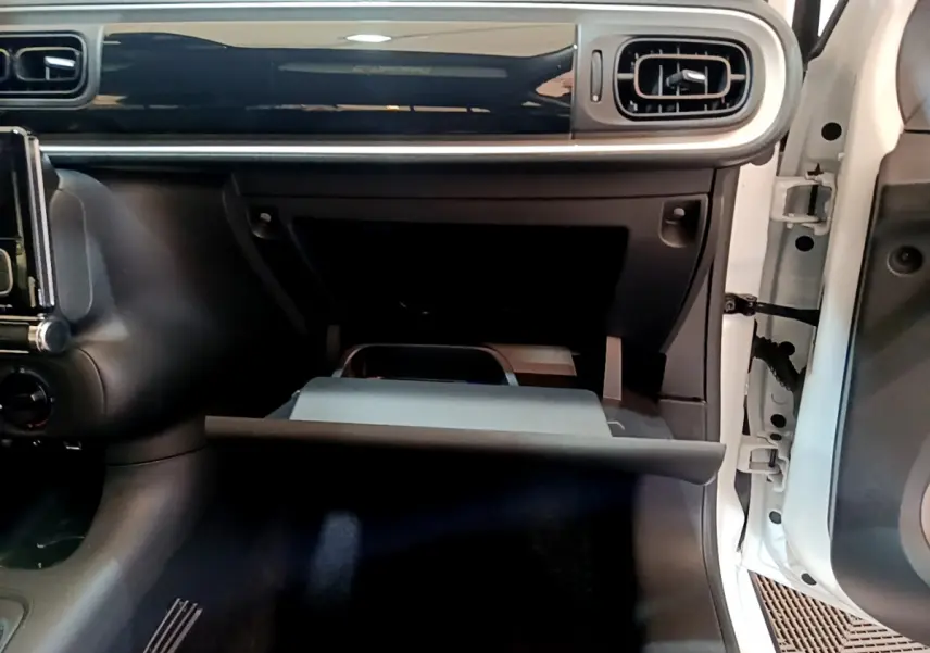 Intérieur de la Citroën C3 blanche 2018, vue côté passager avec boîte à gants ouverte et tableau de bord noir brillant.