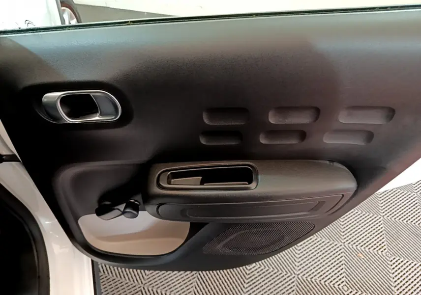 Vue rapprochée de la porte avant gauche blanche d'une Citroën C3 2018 avec poignée noire et haut-parleur intégré.