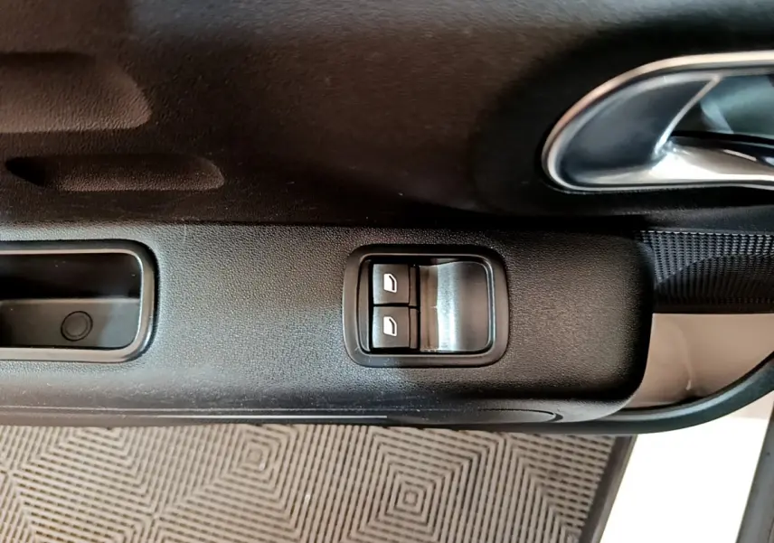 Gros plan sur les commandes électriques des vitres côté conducteur d'une Citroën C3 blanche de 2018.