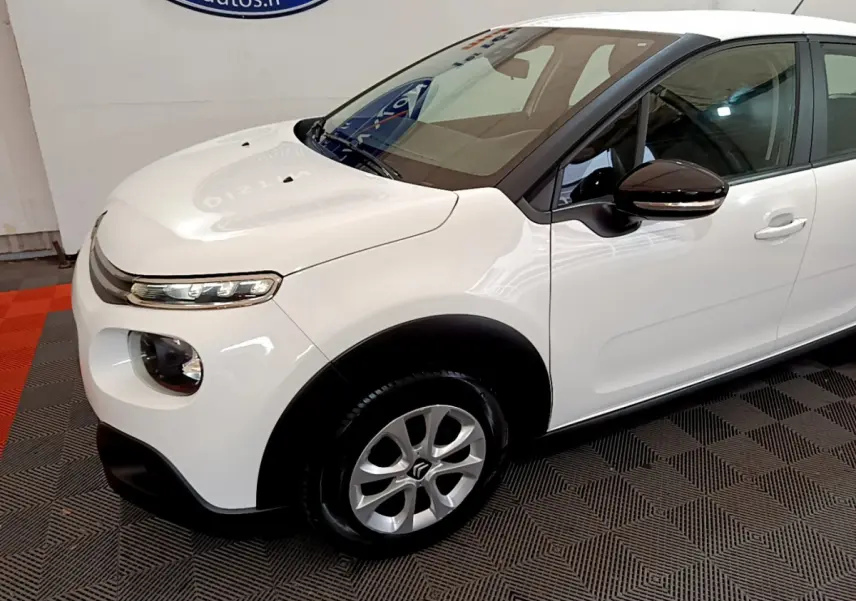 Vue 3/4 avant gauche d'une Citroën C3 blanche avec rétroviseur noir et jante alliage cinq branches.