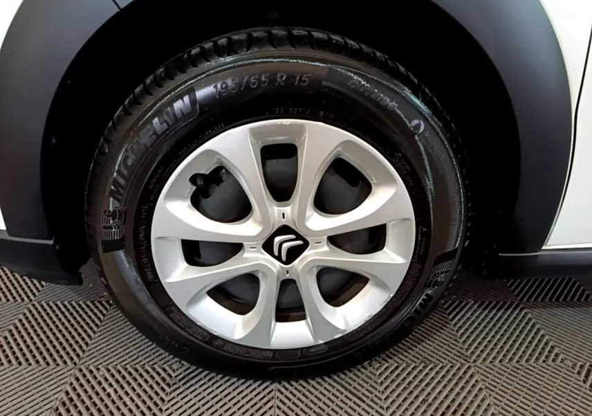 Gros plan sur la roue avant gauche blanche d'une Citroën C3 PureTech 68 BVM Feel avec jante argentée et logo Citroën.