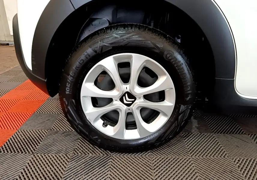 Gros plan sur la roue avant droite d'une Citroën C3 blanche, avec jante alliage et logo Citroën central.