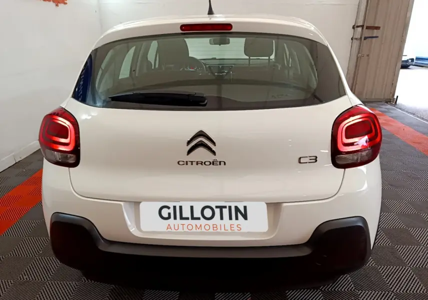 Vue arrière d'une Citroën C3 blanche de 2018 avec feux arrière allumés dans un showroom.
