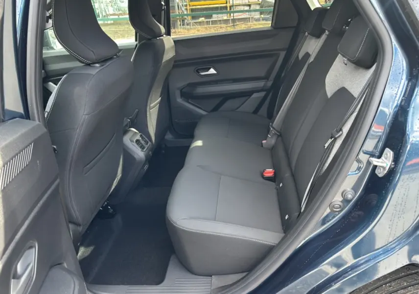 Vue côté gauche sur l’arrière intérieur du Dacia Bigster bleu indigo, montrant la banquette arrière noire et les portes ouvertes.