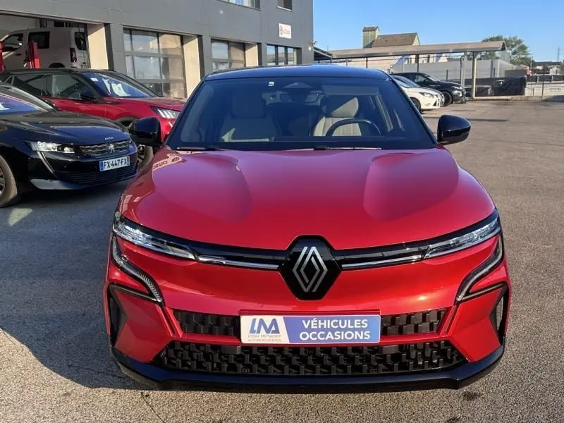 Vue frontale d'une Renault Mégane E-Tech Electric rouge flamme 2023 avec logo noir et plaque "Véhicules Occasions" visible.